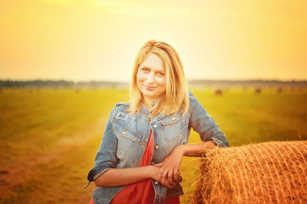 Mulher sexy na pilha de feno no pôr do sol . — Fotografia de Stock