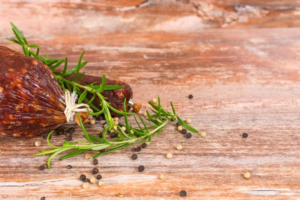 Salami ahumado sobre mesa de madera con romero — Foto de Stock