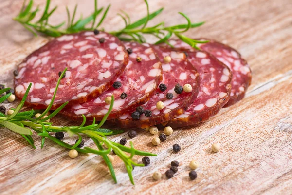 Salame affumicato su tavolo di legno con rosmarino — Foto Stock