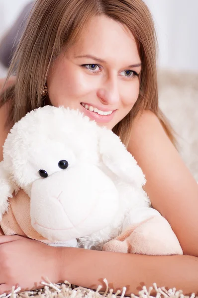 Beautiful  woman wearing pajamas hugging her lamb — Stock Photo, Image