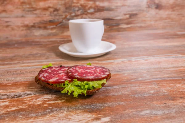 Frukost med salami smörgås och kopp te — Stockfoto