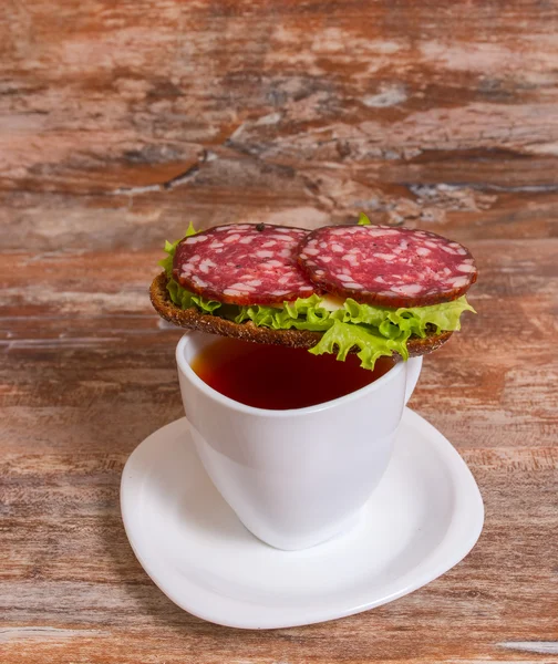 Desayuno con sándwich de salami y taza de té — Foto de Stock