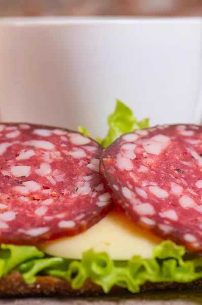 Petit déjeuner avec sandwich au salami et tasse de thé — Photo