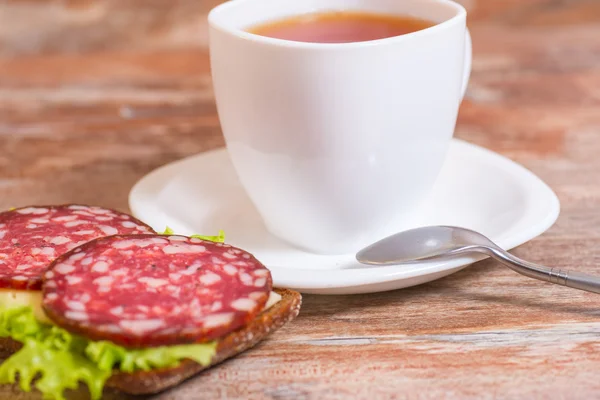 Frukost med salami smörgås och kopp te — Stockfoto