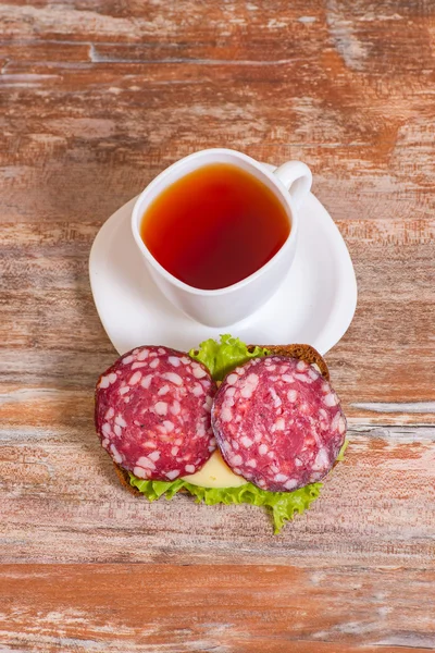 Frukost med salami smörgås och kopp te — Stockfoto