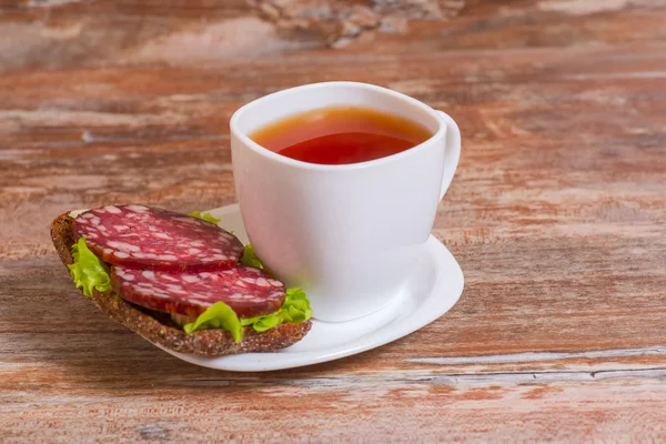 Breakfast with salami sandwich and cup of tea — Stock Photo, Image