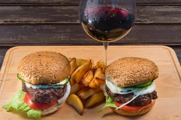 Hamburguesa y papas fritas en un plato de madera . — Foto de Stock