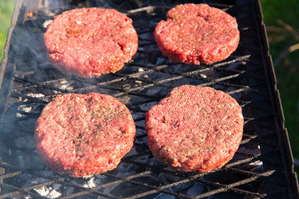 Hamburguesas de carne cruda de cerca en una parrilla — Foto de Stock