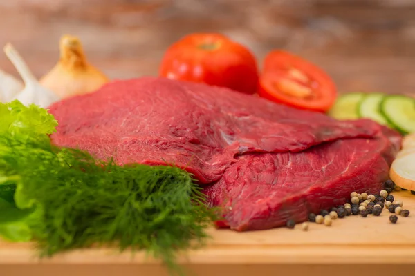 Carne di manzo cruda con verdure su piatto di legno — Foto Stock