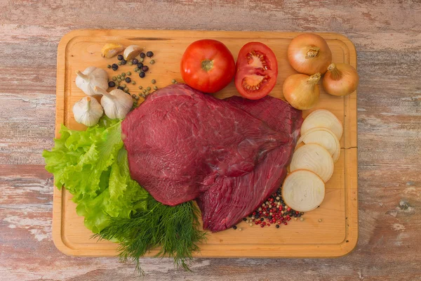 Carne di manzo cruda con verdure su piatto di legno — Foto Stock