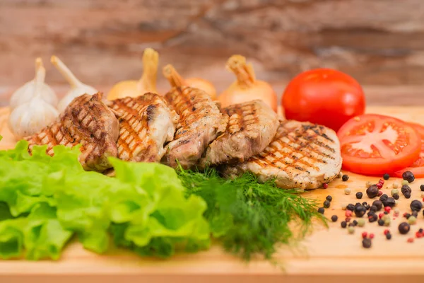 Bistecca alla griglia con verdure su una tavola di legno — Foto Stock