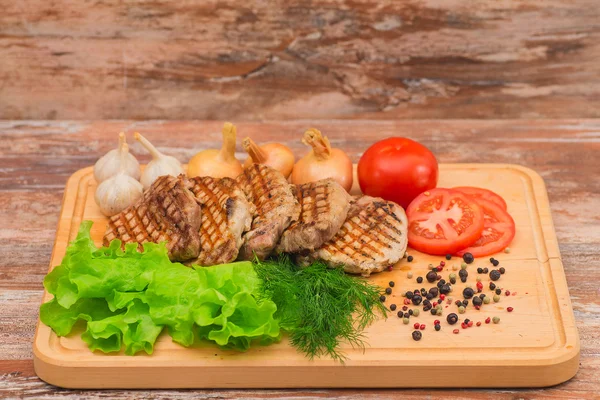 Bistecca alla griglia con verdure su una tavola di legno — Foto Stock