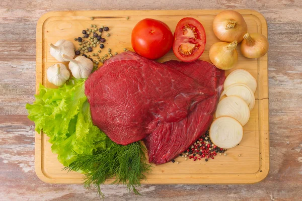 Carne di manzo cruda con verdure su piatto di legno . — Foto Stock