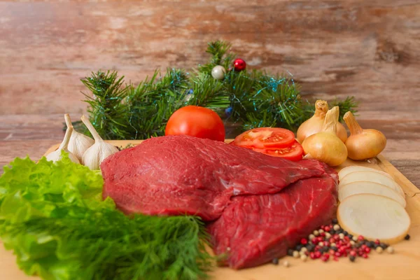 Rå nötkött med grönsaker på träplatta. — Stockfoto