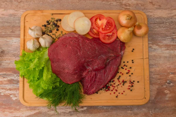 Carne di manzo cruda con verdure su piatto di legno . — Foto Stock