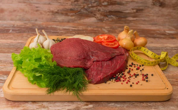 Carne di manzo cruda con verdure su piatto di legno . — Foto Stock