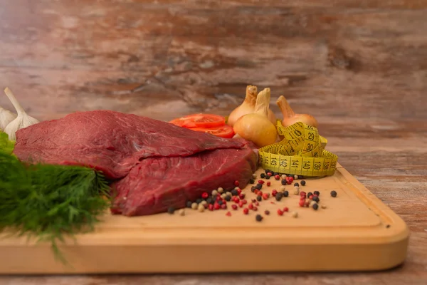 Carne di manzo cruda con verdure su piatto di legno . — Foto Stock