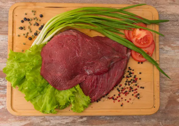 Carne di manzo cruda con verdure su piatto di legno . — Foto Stock