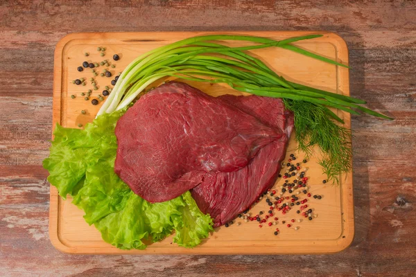 Carne di manzo cruda con verdure su piatto di legno . — Foto Stock