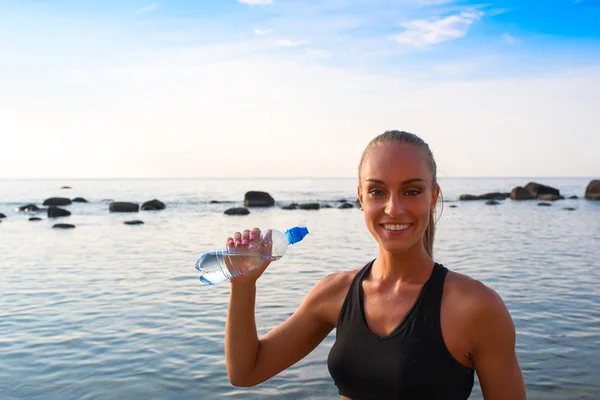 Young female in sports attire rests with water — Stock Photo, Image