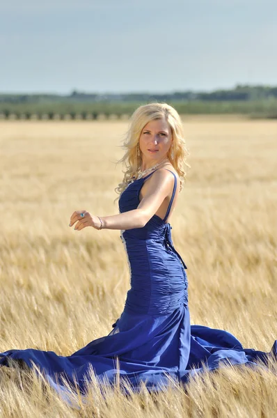 快乐的女人在蓝色的裙子金黄小麦 — 图库照片