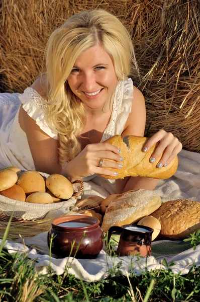 Happy woman posing with bread, milk and hay — Stock Photo, Image