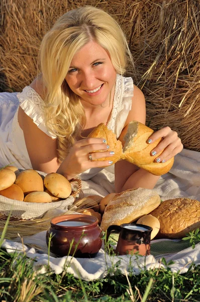 Lycklig kvinna poserar med bröd, mjölk och hö — Stockfoto