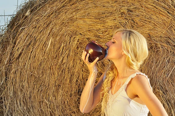 Счастливая женщина пьет молоко из кувшина или камушка — стоковое фото