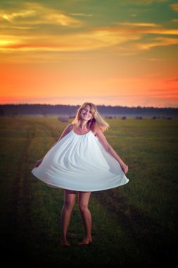 Sarışın kadın bir sahada günbatımı zaman poz