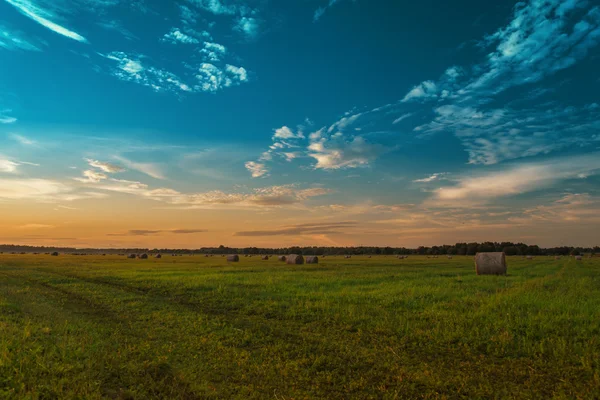 Fim do dia sobre o campo com fardos de feno — Fotografia de Stock