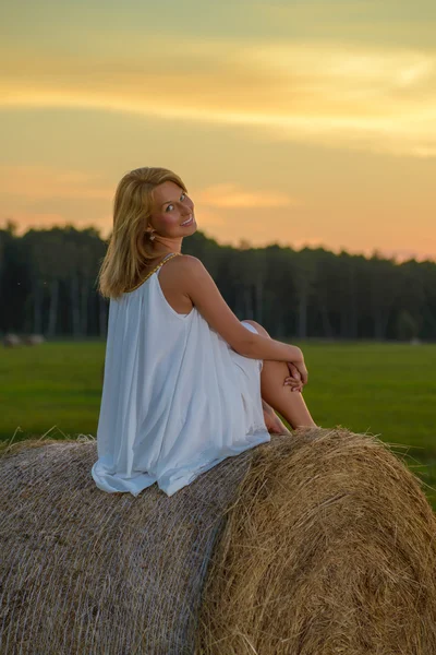 Blonde vrouw die zich voordeed op zonsondergang tijd op een veld — Stockfoto