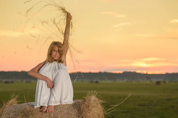 Blond kobieta pozowanie na zachód słońca na polu — Zdjęcie stockowe