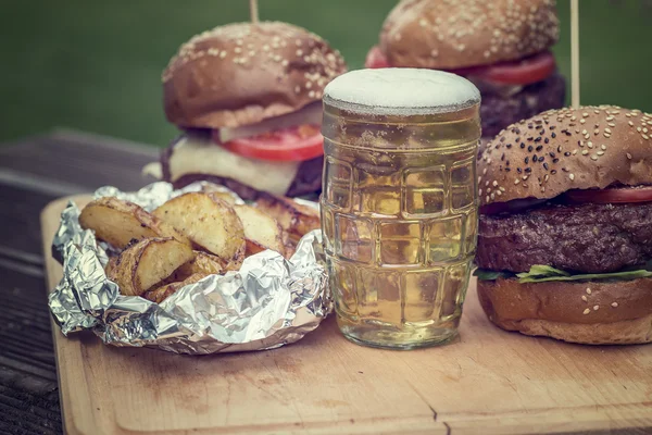 Tasty grilled burger and glass of cold beer — Stock Photo, Image