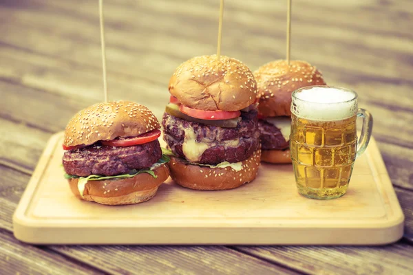 Leckere gegrillte Burger und ein Glas kaltes Bier Stockfoto