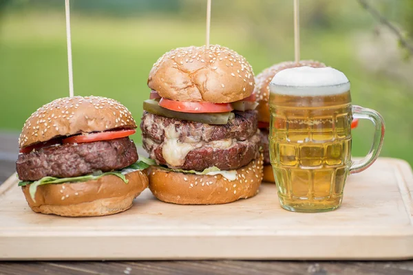 Gustoso hamburger alla griglia e bicchiere di birra fredda — Foto Stock