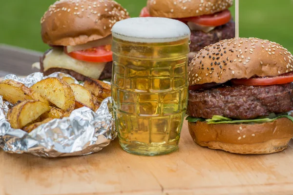 Sabrosa hamburguesa a la parrilla y vaso de cerveza fría . — Foto de Stock