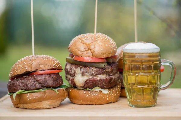 Hamburger grillé savoureux et verre de bière froide . — Photo