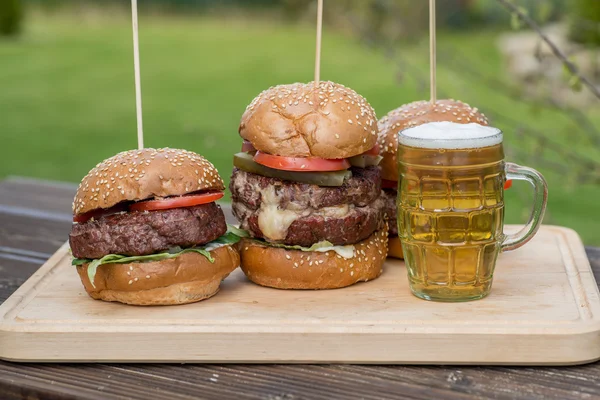 Tasty grilled burger and glass of cold beer. — Stock Photo, Image