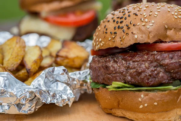 Lekkere gegrilde hamburger, gebakken aardappel en glas bier. — Stockfoto