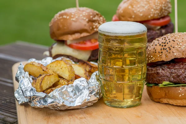 Läckra grillade hamburgare, stekt potatis och glas öl. — Stockfoto