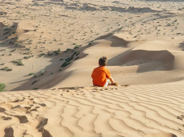 Caucasian boy sitting on sand dune rear view — Stock Photo, Image