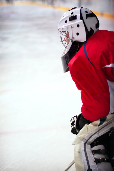 Hockey goalie in generic red equipment protects gate