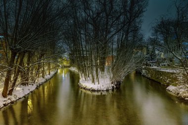 Bir kış akşamında şehir kanalının ortasındaki karla kaplı adanın akşam manzarası