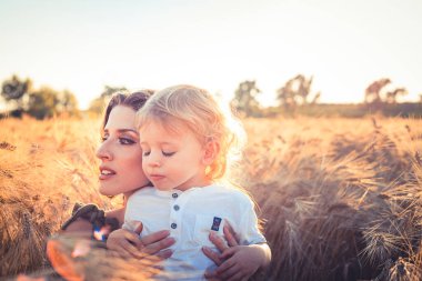 Küçük güzel çocuk buğday tarlasında annesine sarılıyor.