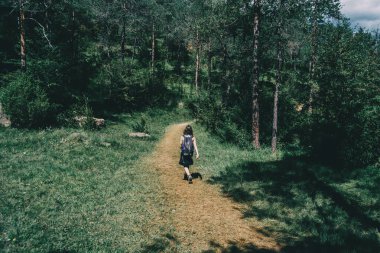 Kadın dağda küçük bir patika boyunca yürüyor.