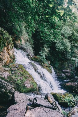 a waterfall in a rustic town in Catalonia, Spain. The river goes down hard illuminated by rays of sun