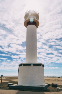 lighthouse on the lonely beach of delta del ebro, tarragona, spain. The day is cloudy and windy.
