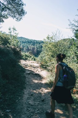 Kadın dağda küçük bir patika boyunca yürüyor.