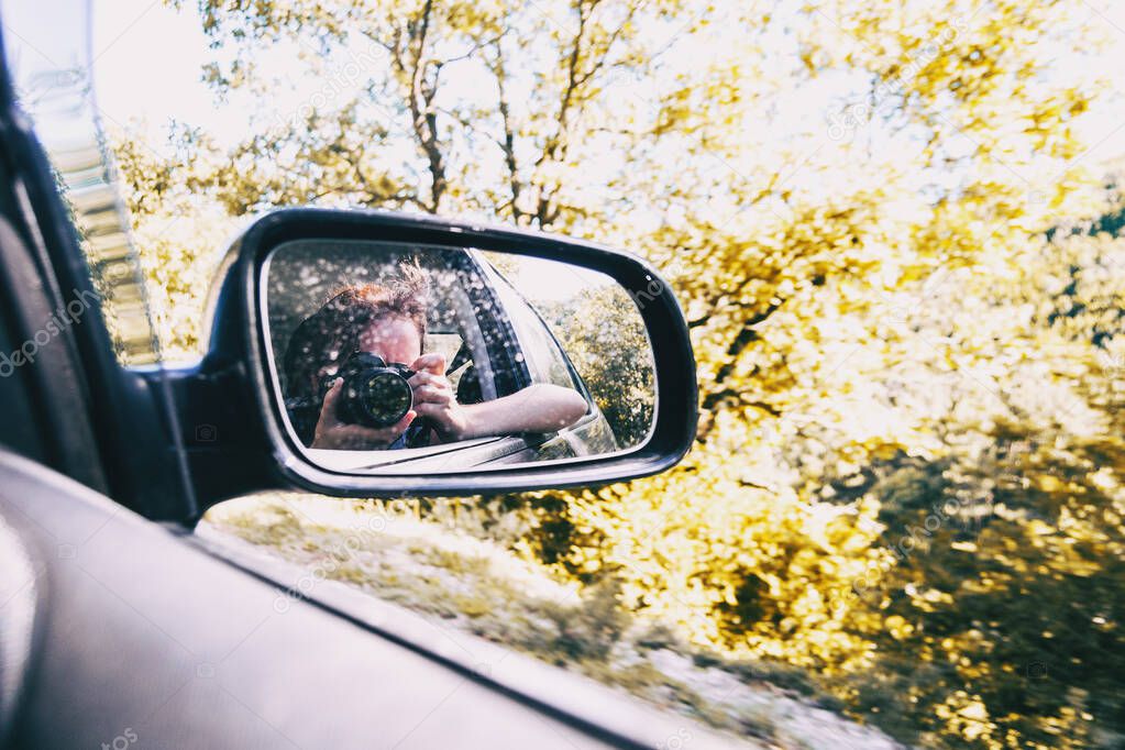 Selfie of a girl in the rear view of the car while the car is running. The girl wears her hair tied up and blows her away with the wind.
