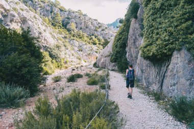 Bulutlu bir yaz gününde Katalonya 'da dağ yolunda yürüyüş yapan bir kadın.